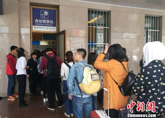 自助售票处前排队取票的旅客。　隋峰 摄